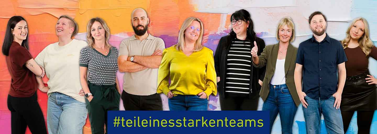 A group of ComTS employees standing together in front of a colorful background with the slogan “#teileinesstarkenteams”.