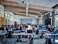 Certification with attendees using laptops in a bright room.
