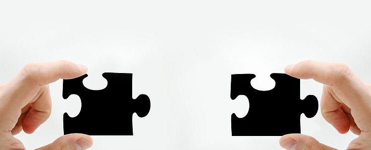 Two hands with matching puzzle pieces